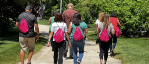 A group of eight adults wearing red backpacks participating in a team building activity.