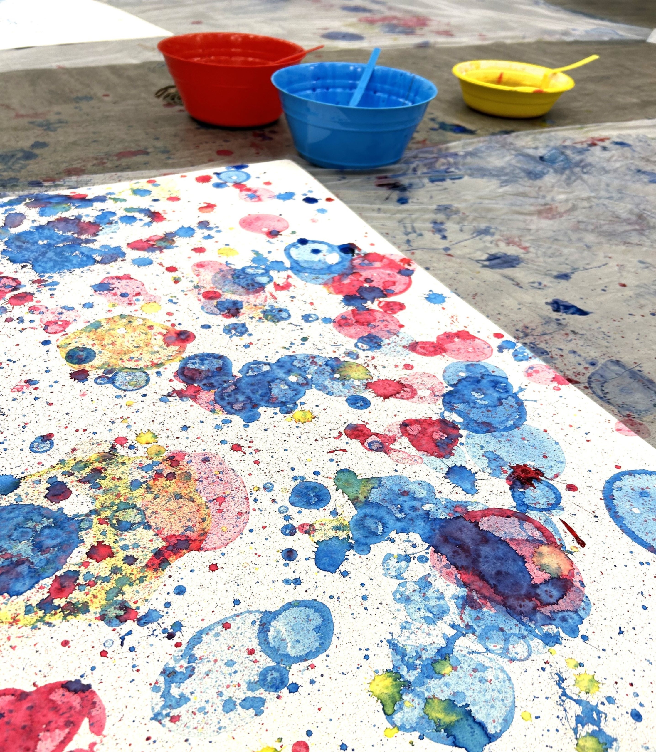 Red, blue, and yellow paint splatters on a white canvas