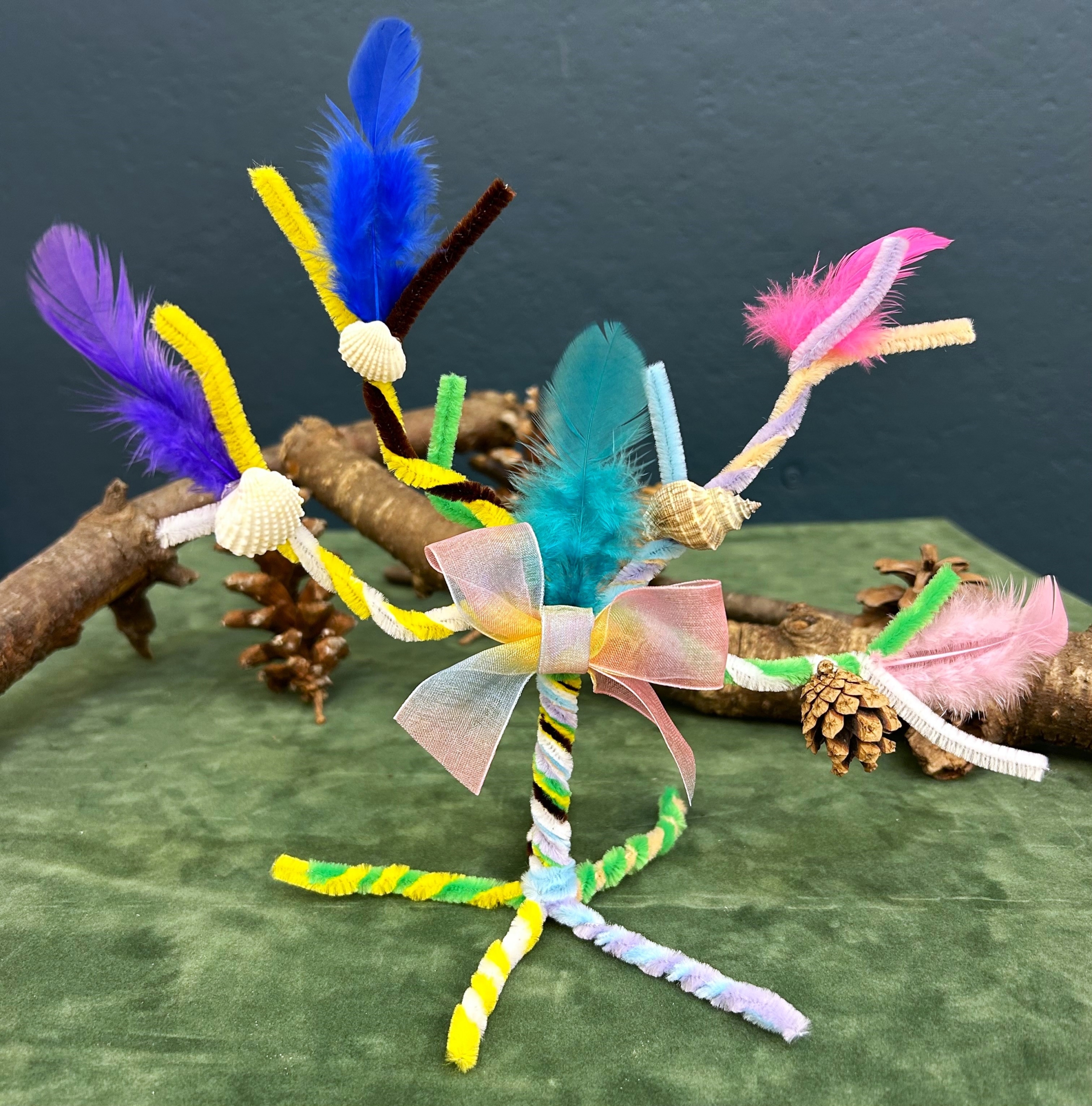 A tree sculpture made with colorful pipe cleaners and feathers.