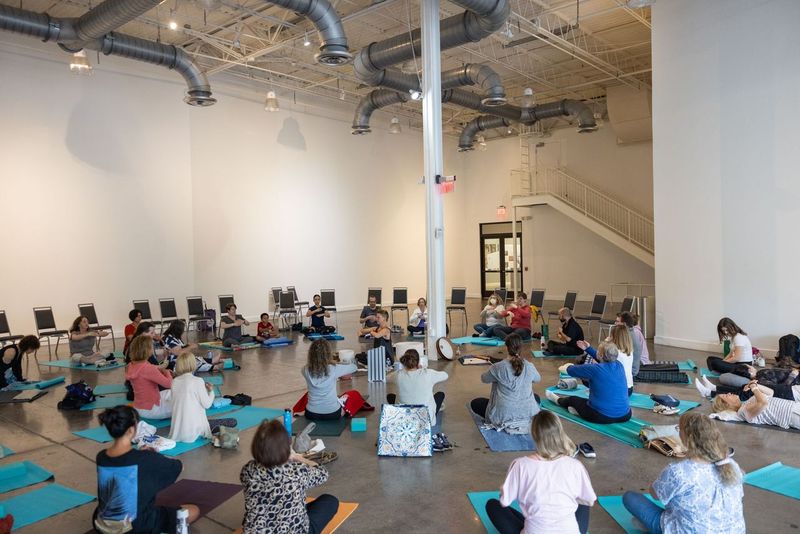 A room full of people seated on blue yoga mats during a sound bath.