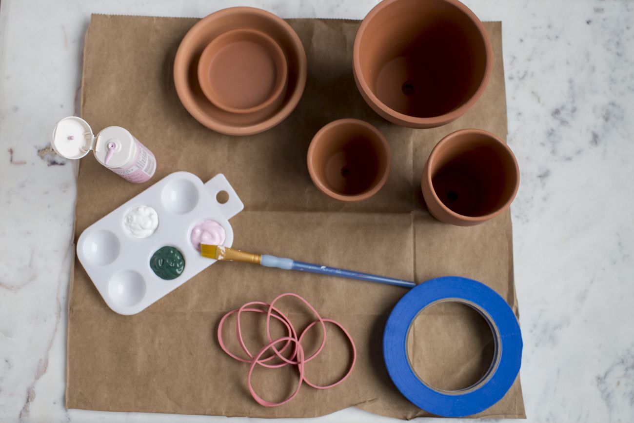 Terracotta pots and painting supplies on a table.