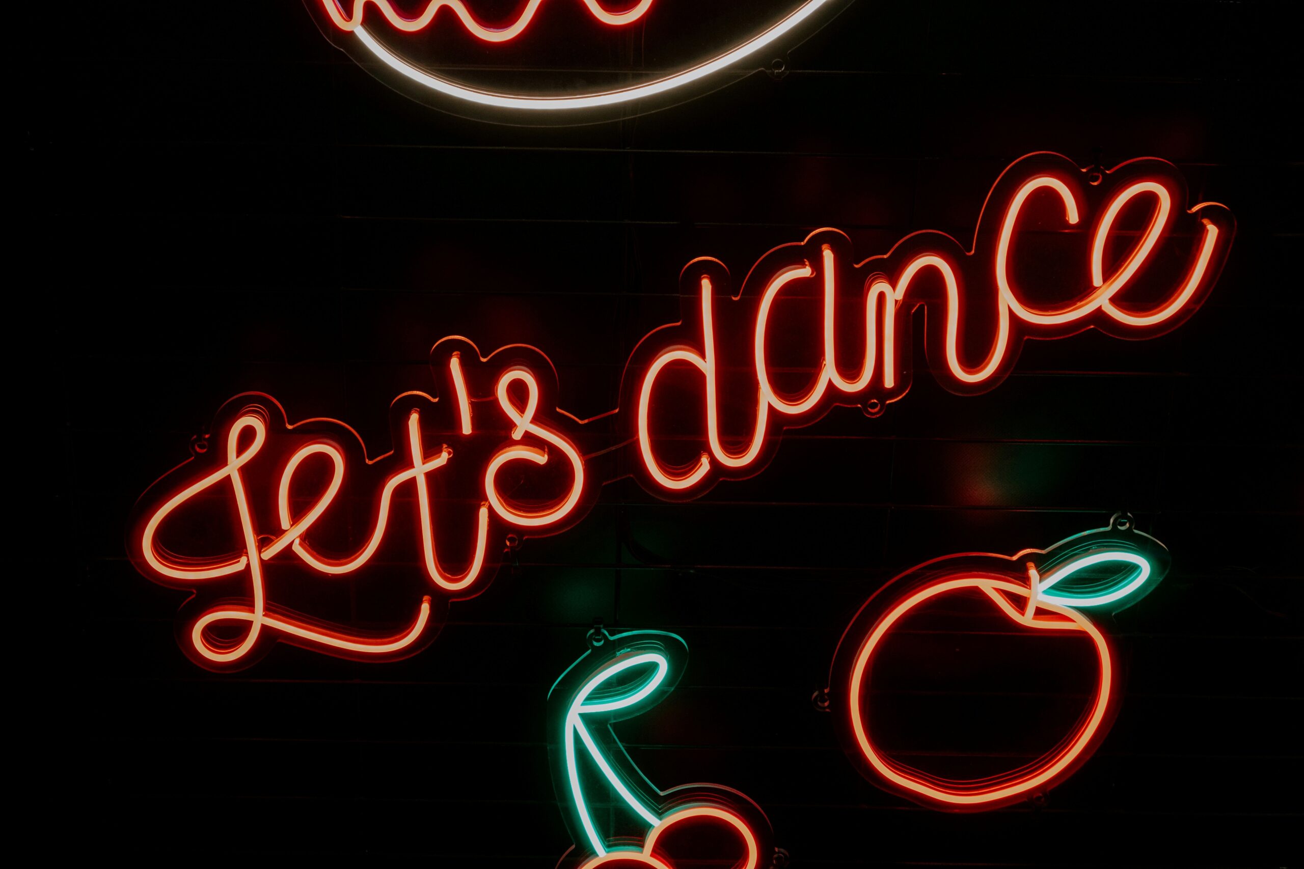 Red neon letters against a dark background that say let's dance.