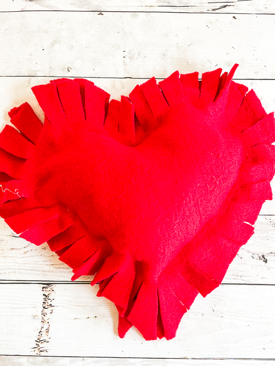 A red fringed heart pillow.