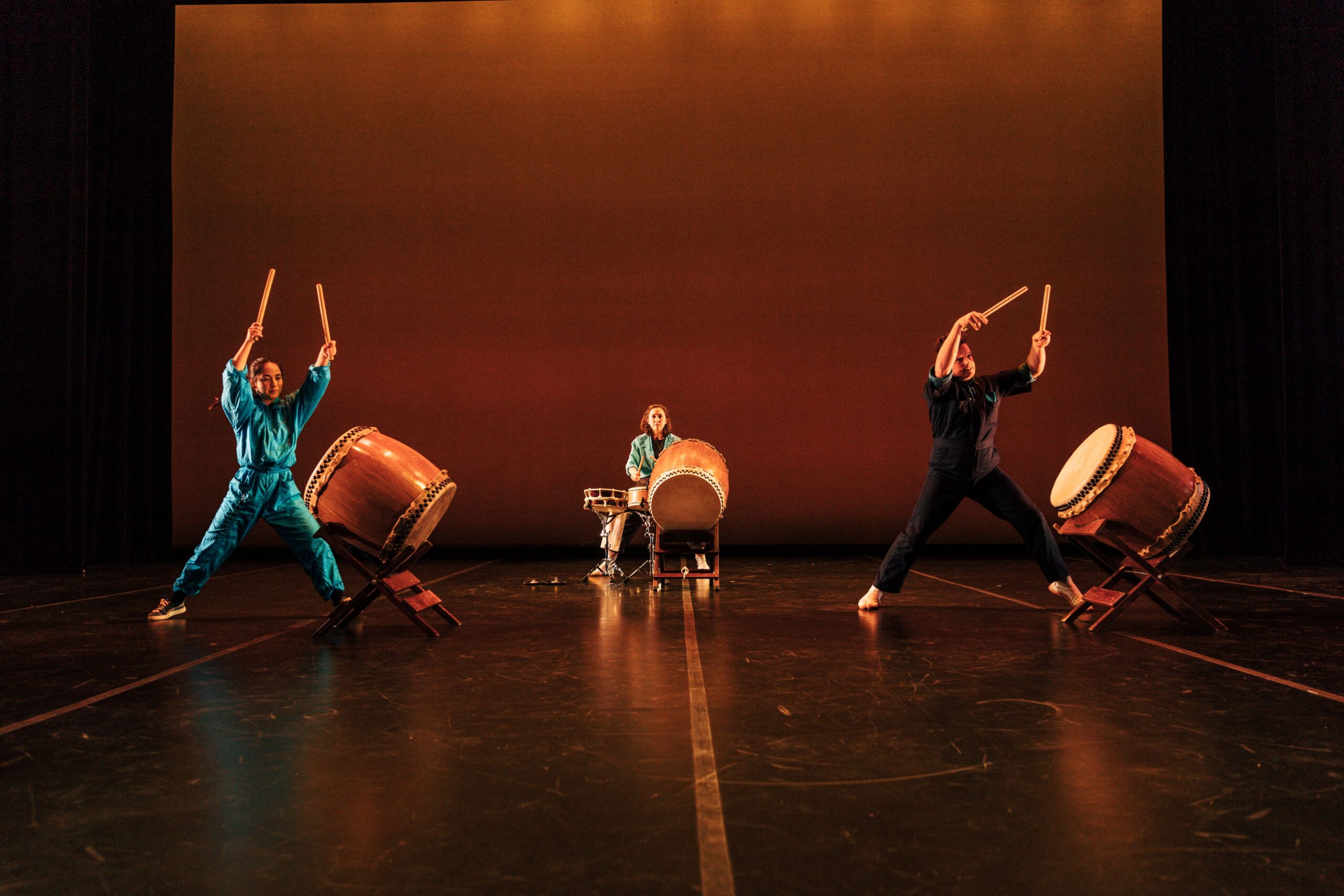 Casual Fifth performing on three sets of drums at a concert.