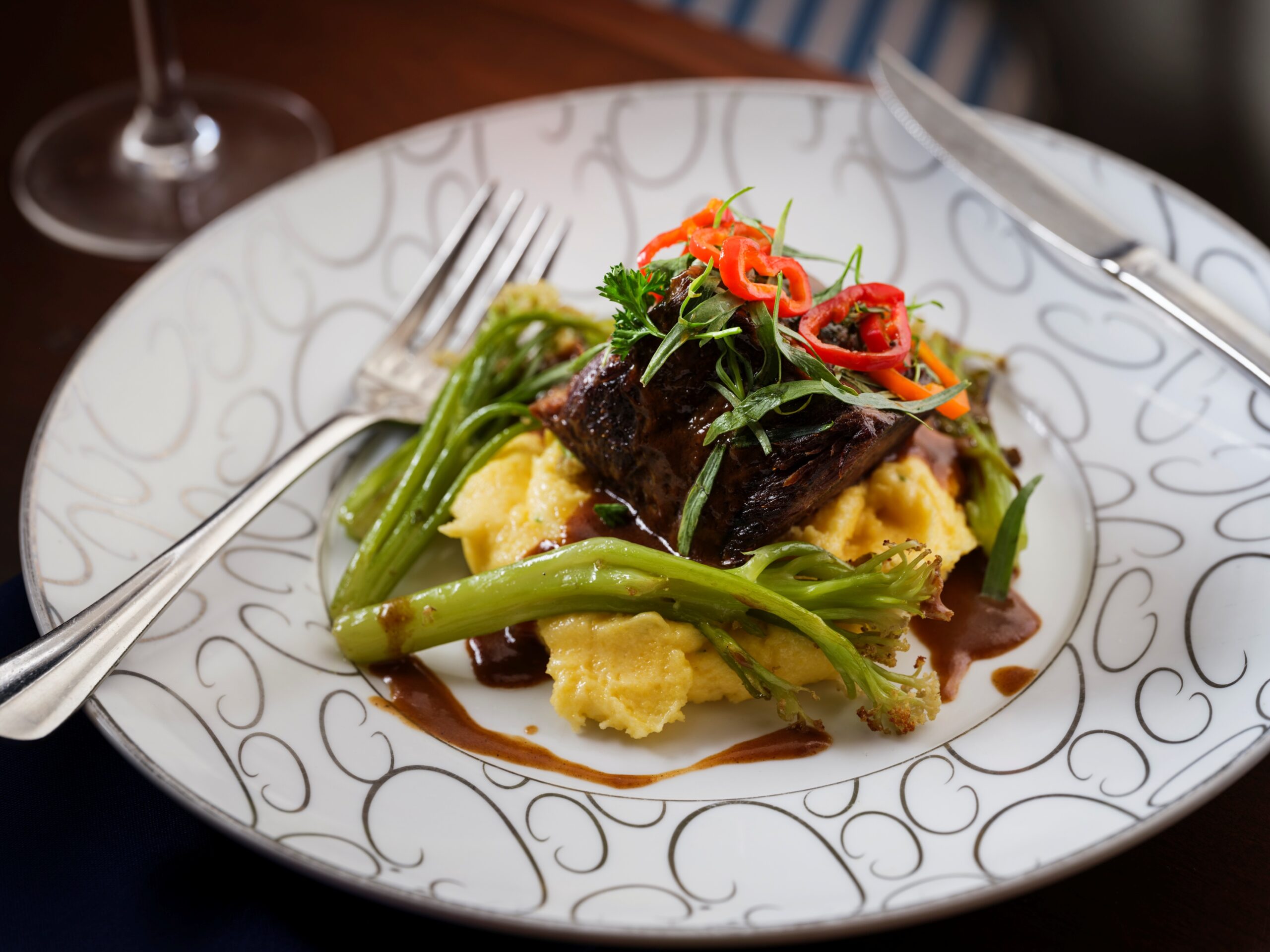 A close up of a dinner plate with asparagus, polenta, and short rib.