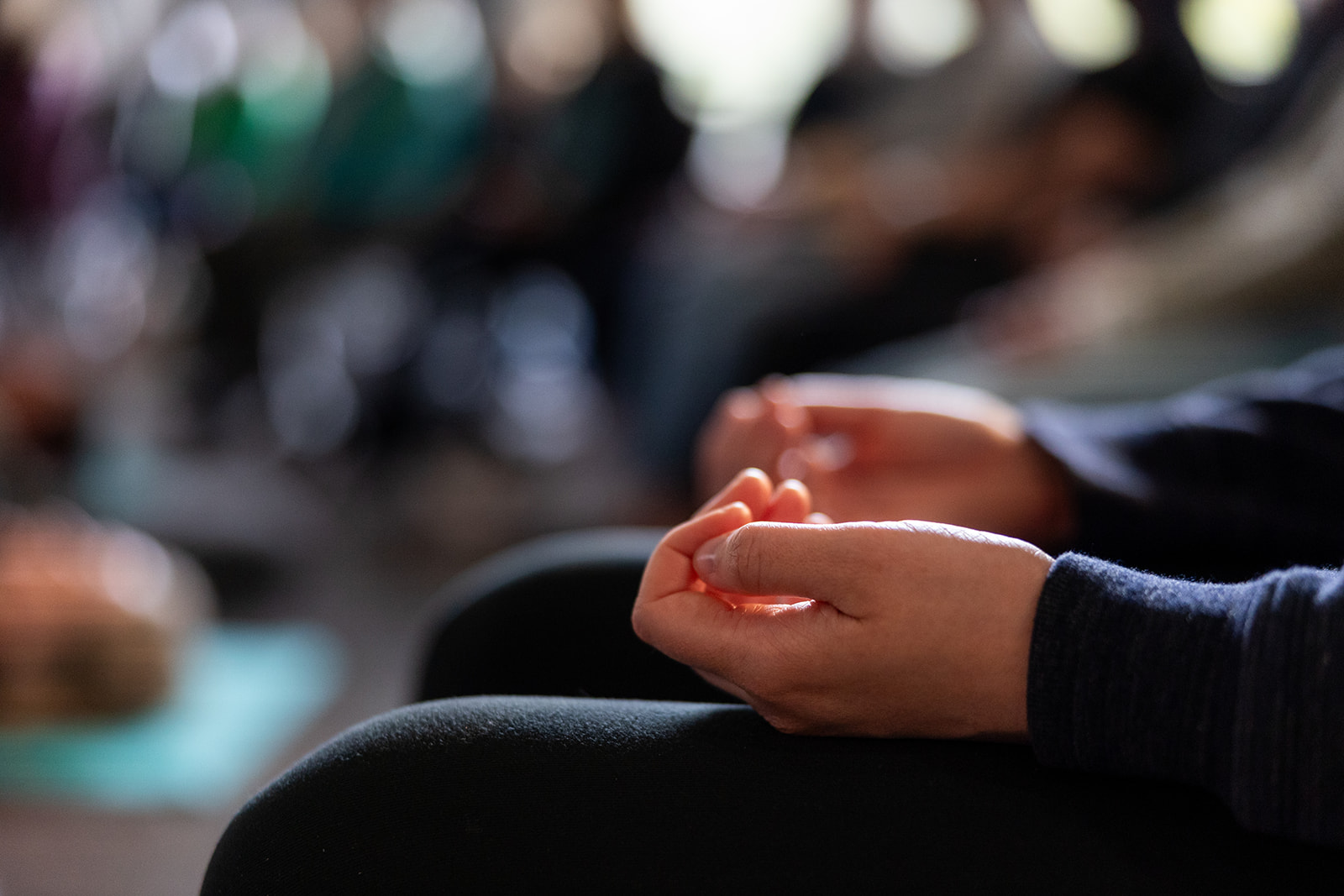 A closeup of a person's hands facing upwards on their legs during a wellness workshop.