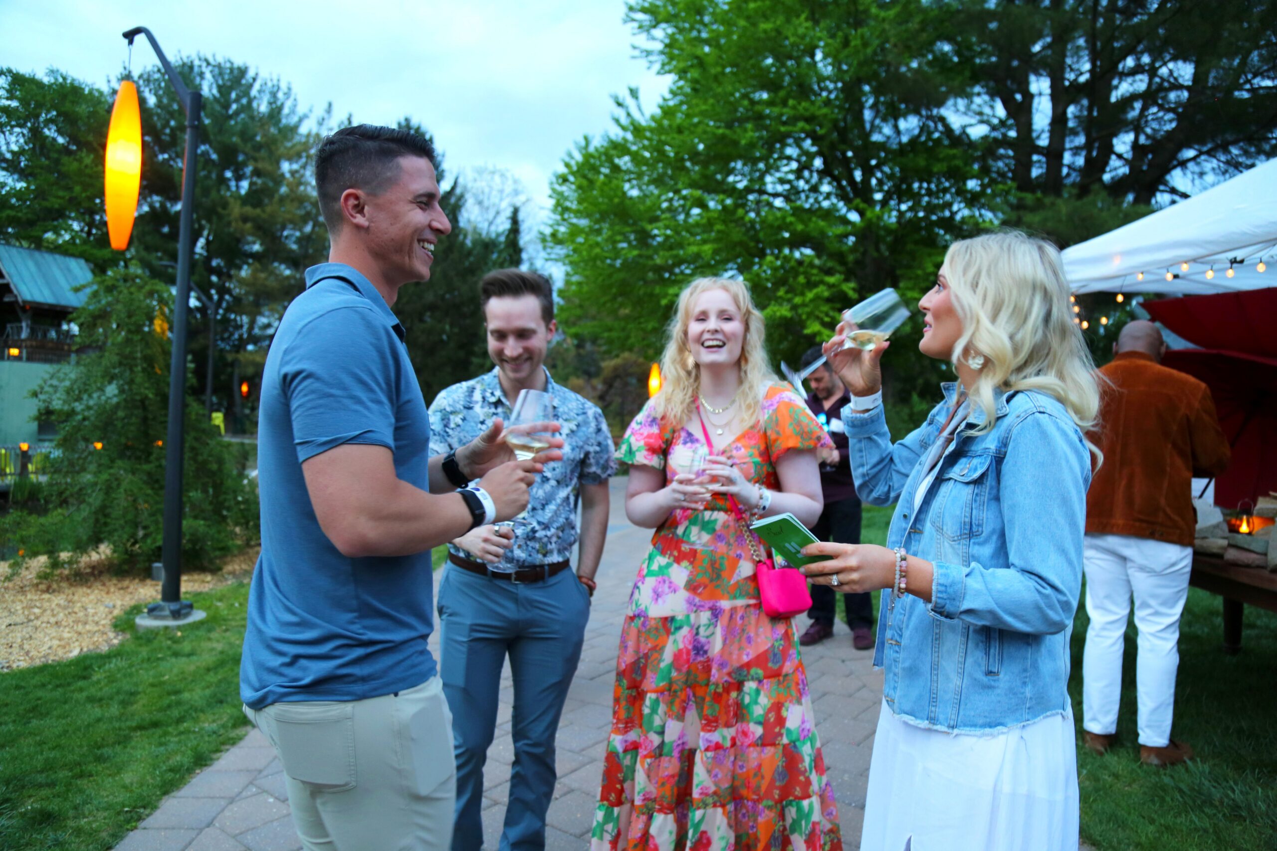Two men and two women in a group smile and laugh while holding wine glasses.