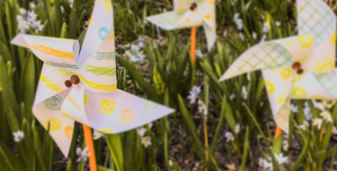 Three homemade pinwheels in the grass.