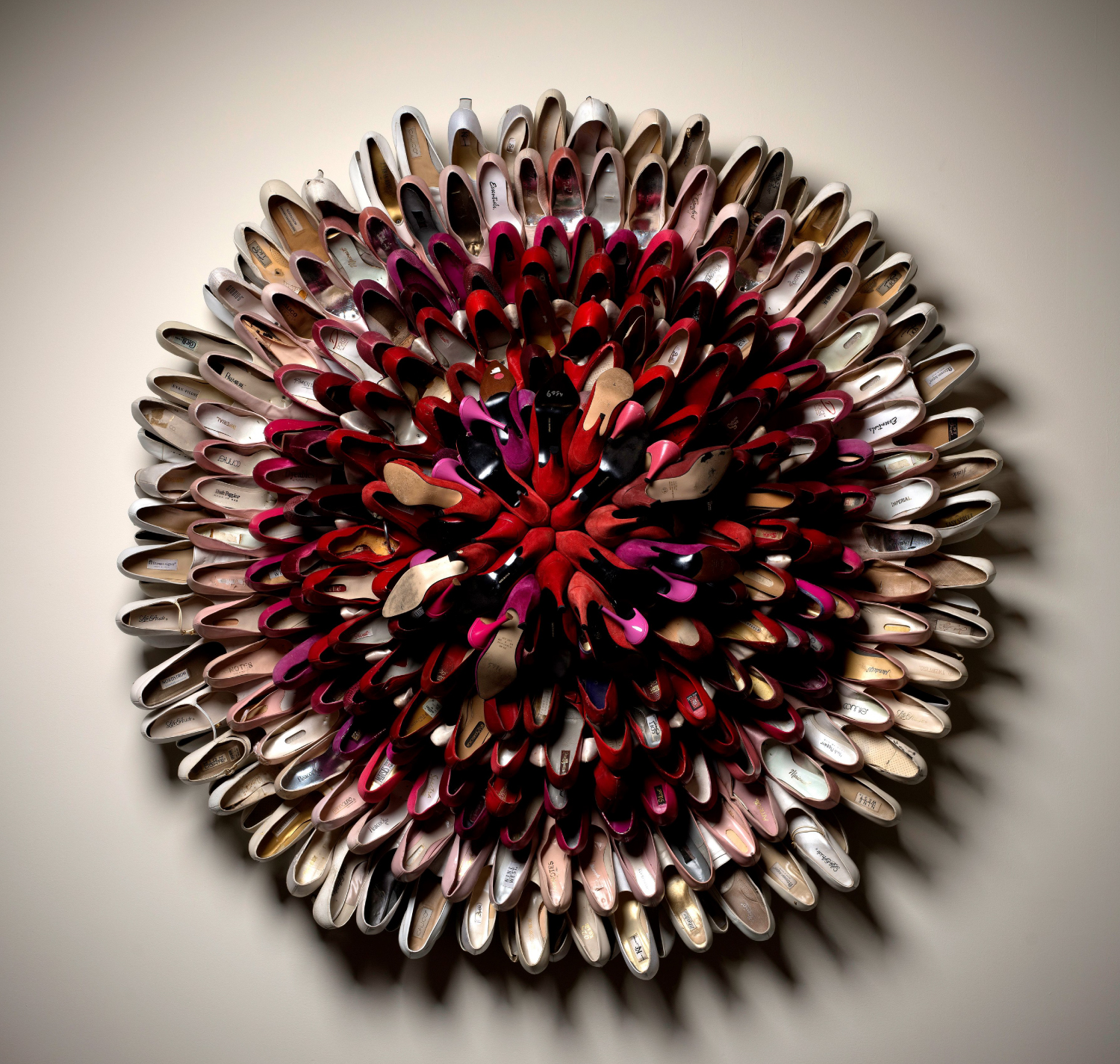 Pretty in Pink by Willie Cole. Hung on a wall, it is a sculpture made up of circles of red, white, and pink high heels.