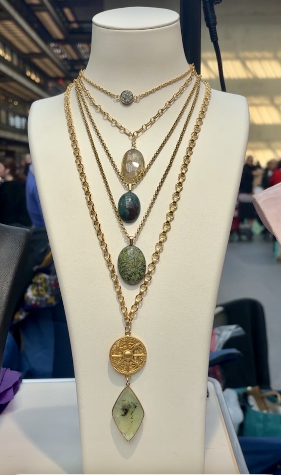 A white jewelry display with a bejeweled necklace on display.