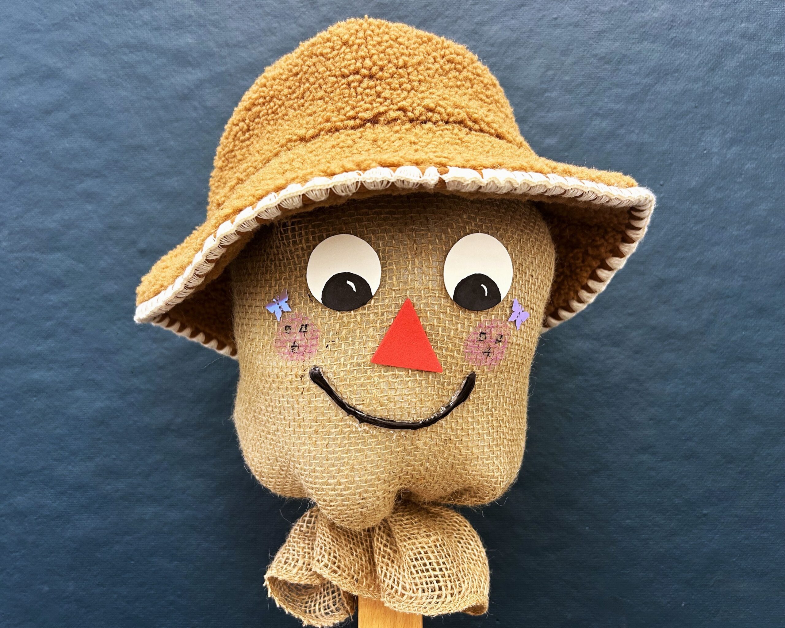 A scarecrow head with a painted face and hat.