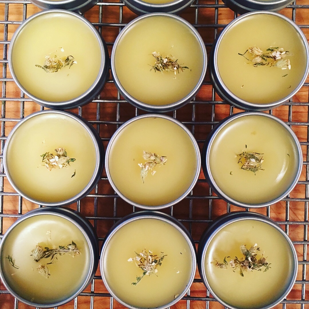 Nine tins of herbal salves arranged in a 3 by 3 pattern.